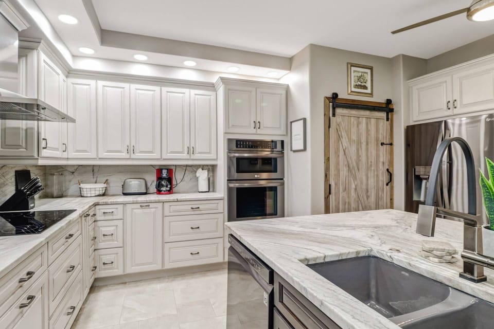 The kitchen offers granite counters and backsplash, sink island, tray ceiling with fan and unique barn door laundry space.