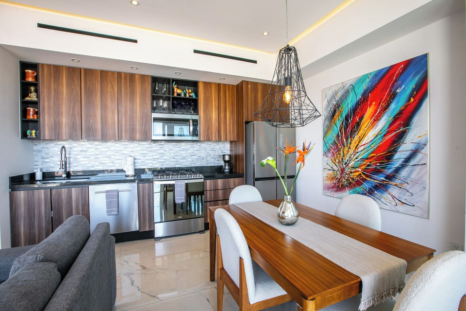 Your sleek kitchen flows seamlessly into the dining area, where vibrant artwork and warm wood create the perfect backdrop for memorable meals.