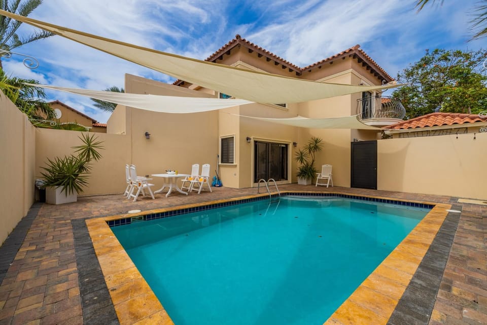 Large pool with shades and outdoor dinning.