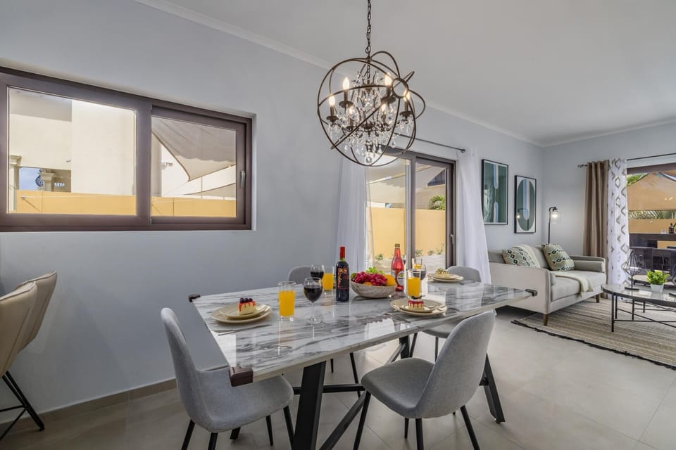 A sufficient dining area with a four-seater dining table. Decorated with an elegant pendant chandelier.