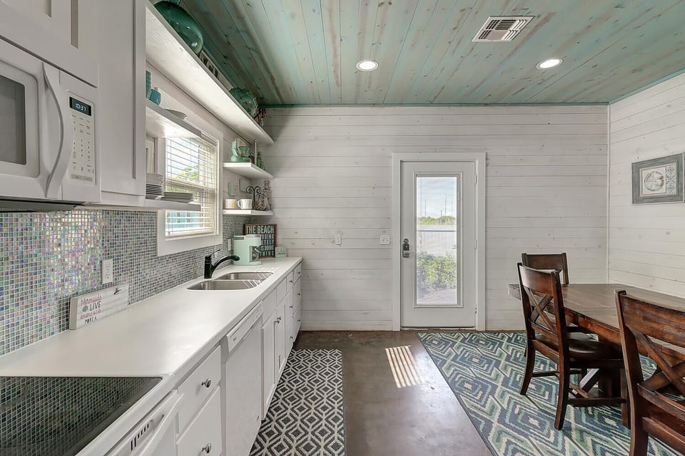 Your fully equipped kitchen blends coastal charm with modern convenience, featuring gleaming appliances and sea-glass accents for memorable meals.