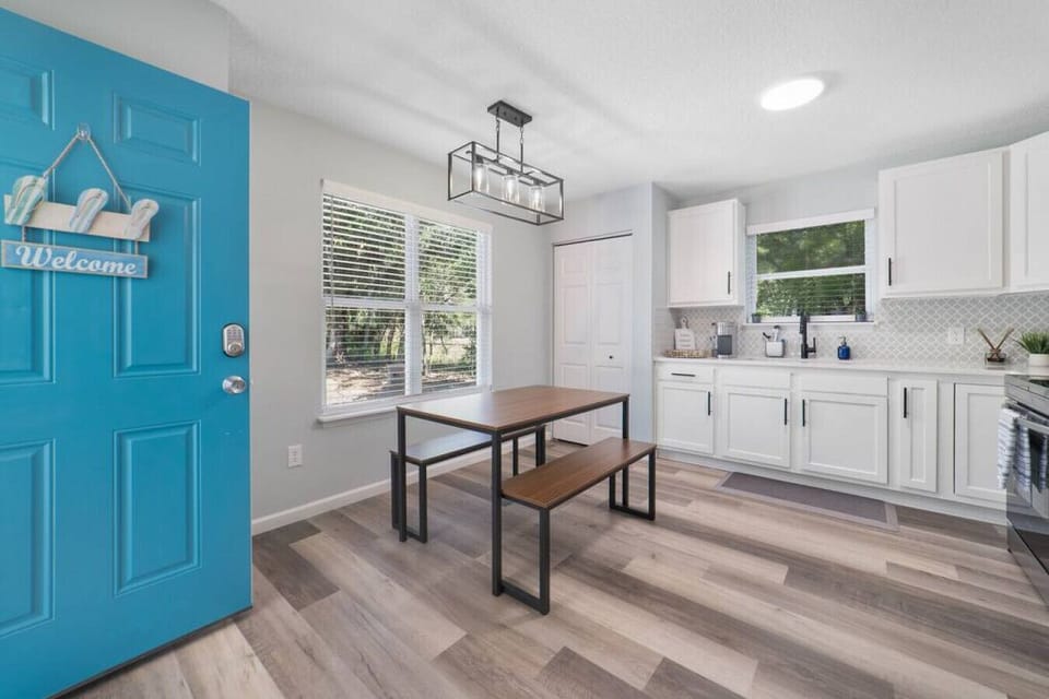 The renovated kitchen features quartz countertops, white cabinets & dining area.