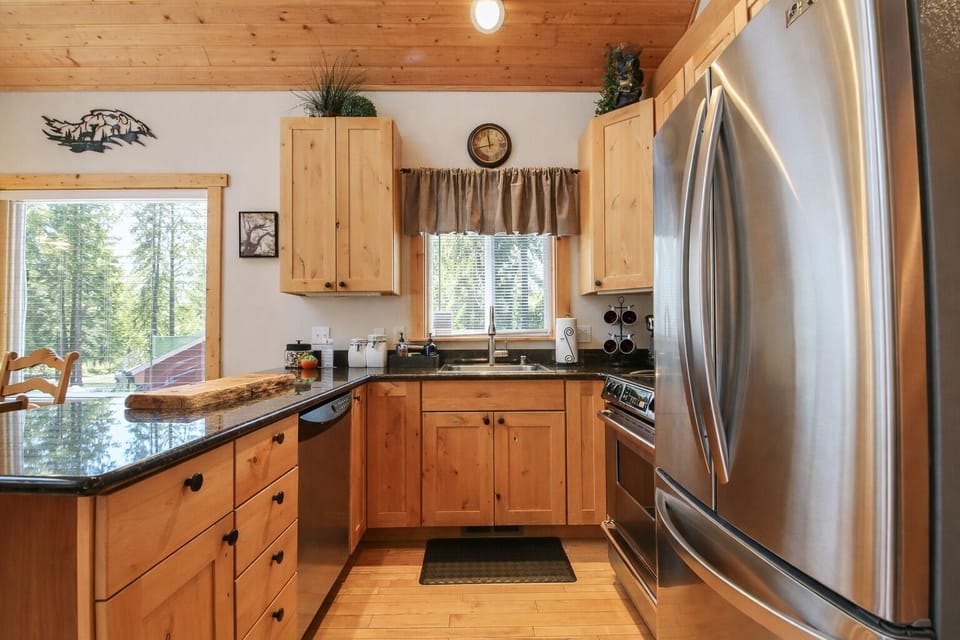 The fully equipped kitchen awaits with warm wood cabinets, granite counters, and stainless appliances for memorable home-cooked meals.