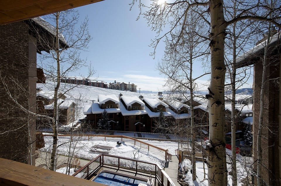 Breathtaking winter vista framed by aspen trees, showcasing snow-covered slopes and neighboring mountain lodges in this picturesque alpine setting.