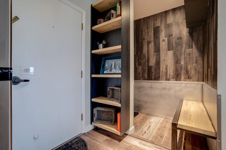 Step into your cozy entryway with rustic wood walls, built-in storage shelves, and a charming bench perfect for settling in.