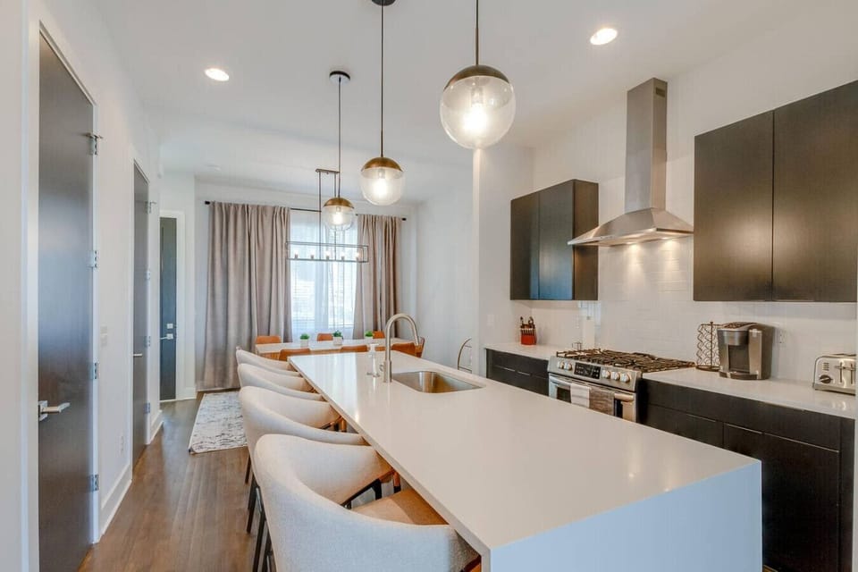 Sleek kitchen with an island, bar stools, stainless appliances, and pendant lights