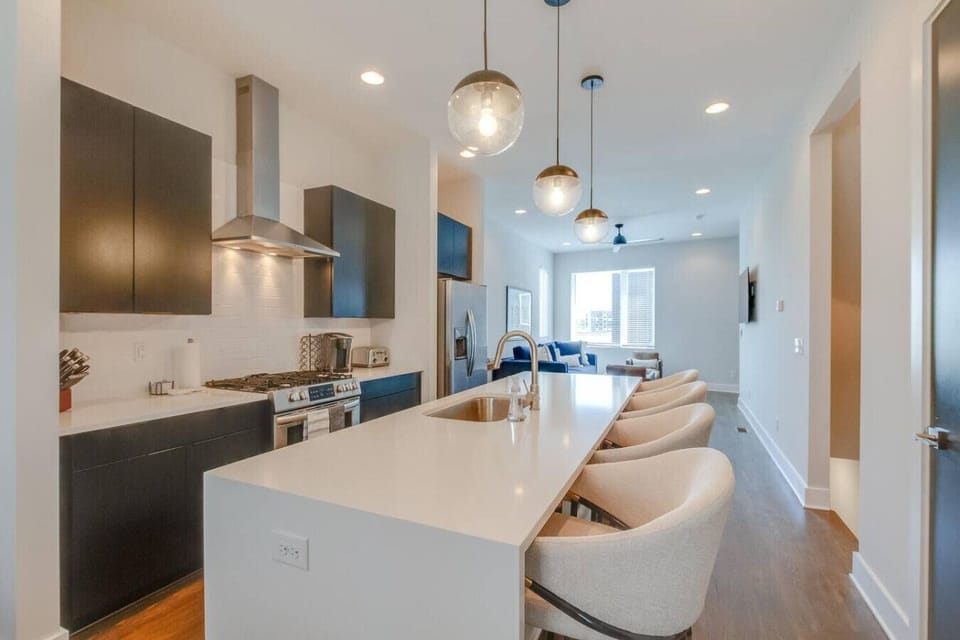 Modern kitchen with a large island, bar seating, and pendant lighting open to the living area