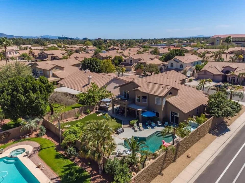 Aerial view of a desert resort community featuring red-tiled roof homes, palm trees, and private pools throughout the neighborhood.