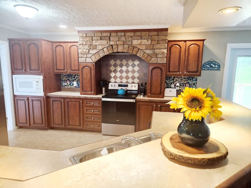 Part of the kitchen with the microwave and stove and plenty of cabinets pictured