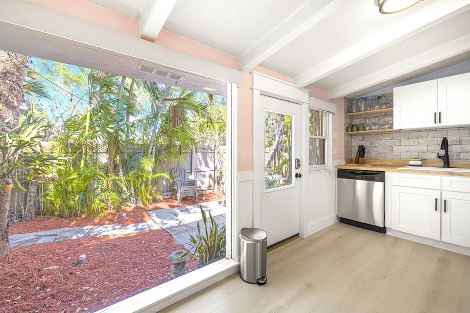 Kitchen area with large window looking out to sunny patio.