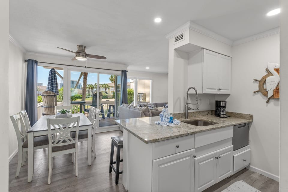 Picture yourself preparing fresh coffee in this bright kitchen, then gathering around the dining table as natural light streams through doors opening to your private balcony with coastal views.