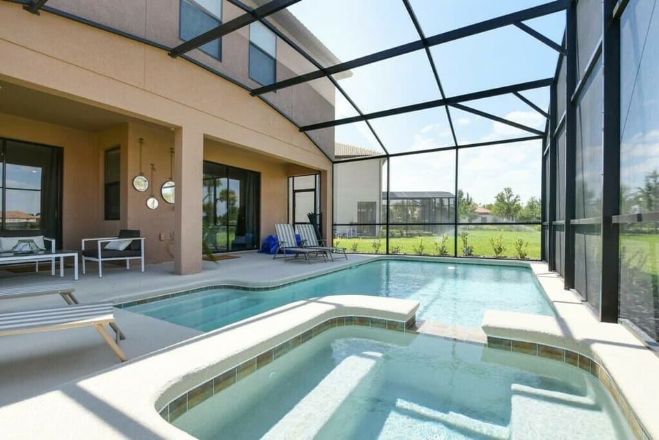 Step outside to your private oasis, featuring a sparkling pool and hot tub framed by sleek glass screening. Relax on stylish lounge chairs while soaking up the sun, all set against a tranquil backdrop of lush greenery.
