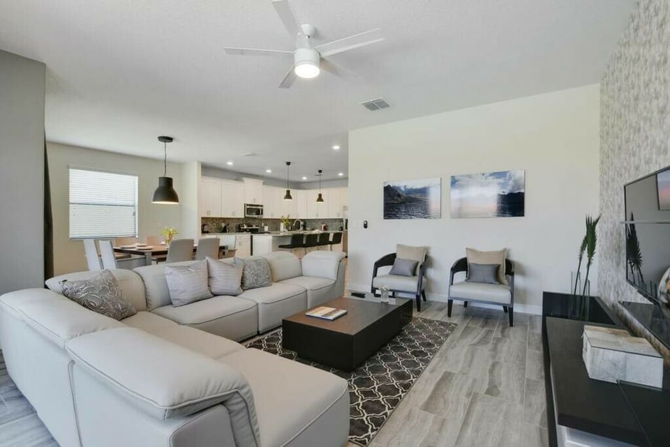 Unwind in the stylish living area with a plush light gray sectional and chic armchairs, ideal for relaxing after your adventures. The open layout seamlessly connects to a modern kitchen, making it perfect for cozy gatherings.