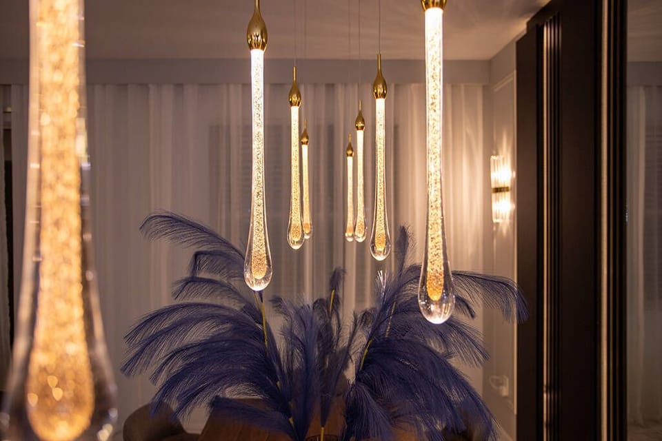 Enjoy the inviting glow of stylish pendant lights and soft curtains, while a vibrant blue palm plant adds a tropical touch to create a sophisticated ambiance during your stay.