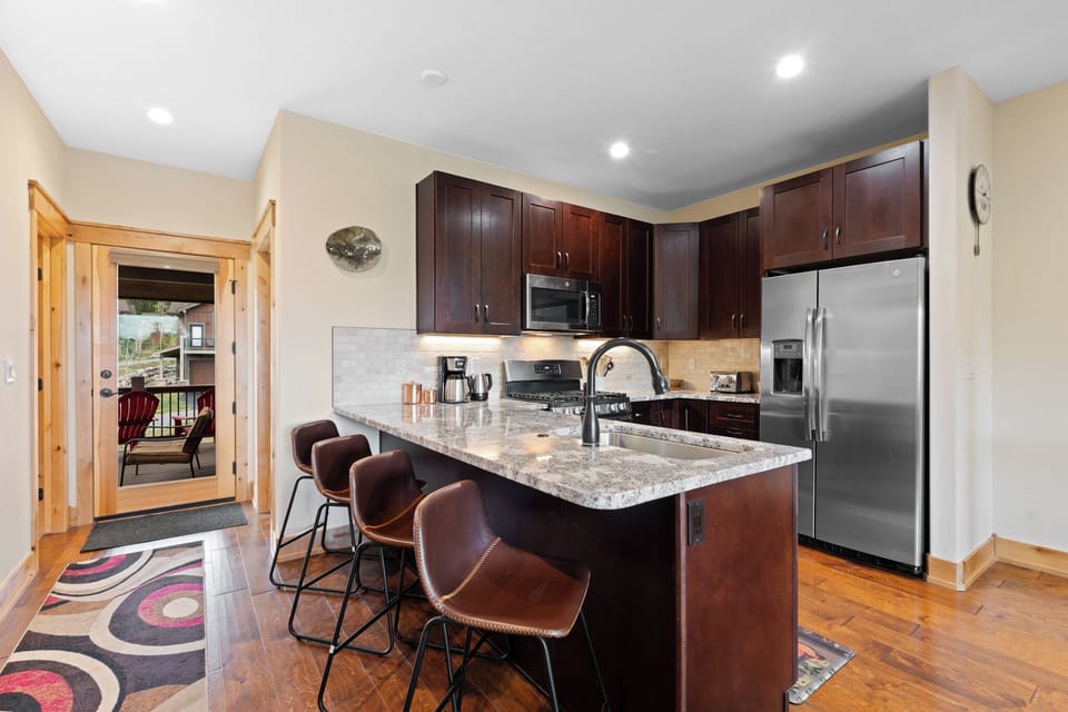 Step into a fully equipped kitchen with granite counters, stainless appliances, and bar seating perfect for morning coffee or casual meals with friends.