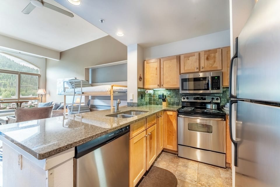 Your fully equipped kitchen opens to a bright living space with bunk beds and stunning mountain views through floor-to-ceiling windows.