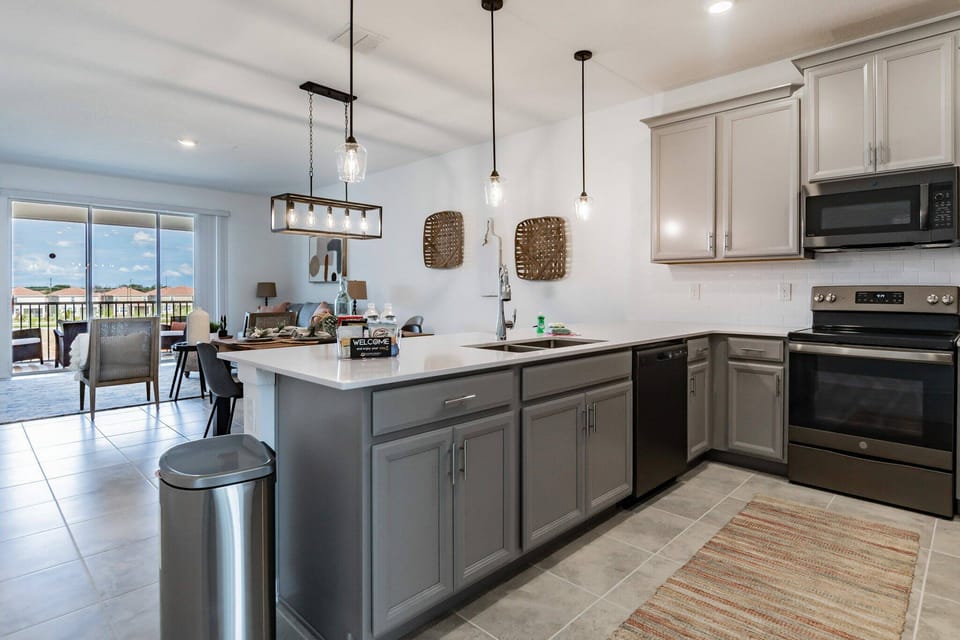 Experience a beautiful kitchen with sleek grey cabinets and modern stainless steel appliances, enhanced by stylish pendant lighting.