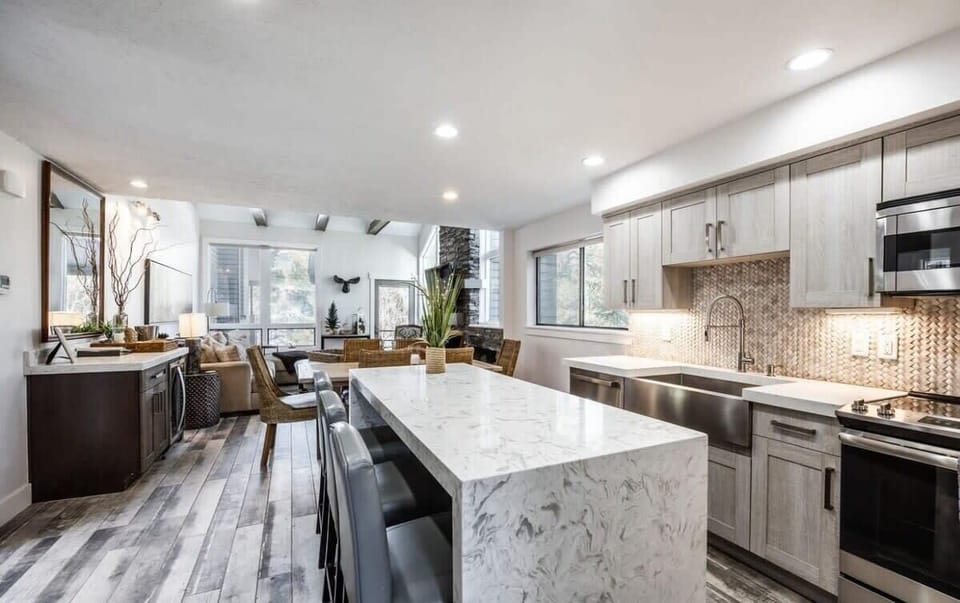 The stunning kitchen features top-of-the-line finishes, a waterfall island/bar where you can seat and serve three, beautiful tile backsplash throughout and stainless steel appliances.