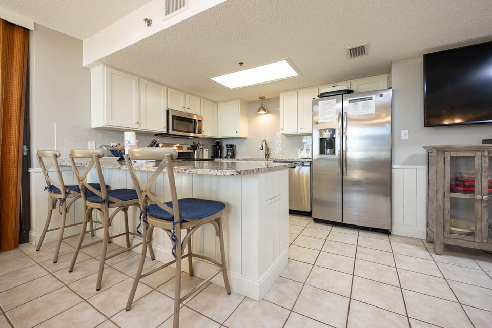Modern kitchen featuring granite countertops, sleek cabinetry, coffee station, and bar seating for a relaxed dining vibe