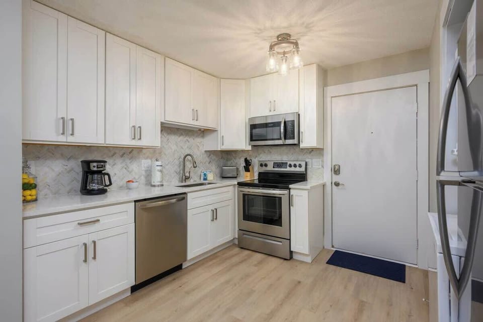 A clean, modern kitchen with white cabinetry and stainless steel appliances.