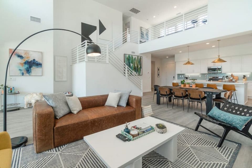 Open-concept living space w/ high ceilings, cozy sofa & seamless flow into dining area