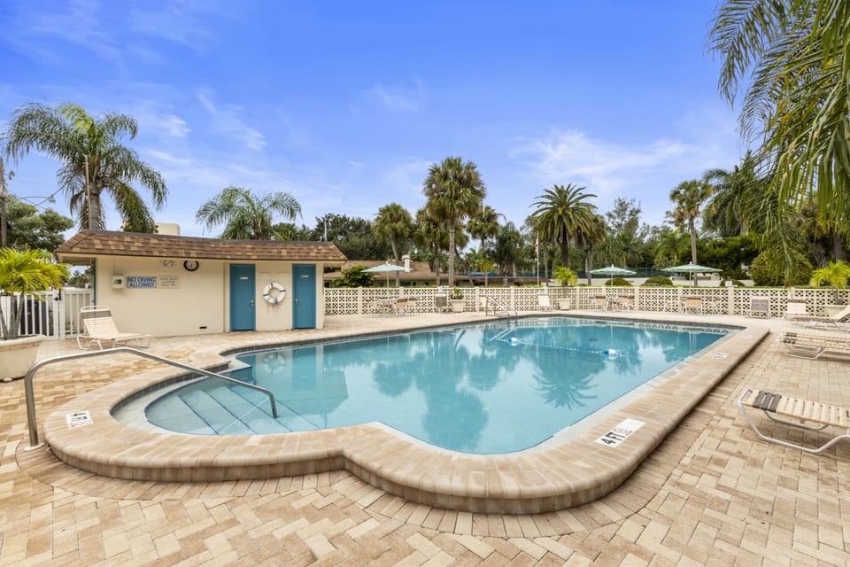Outdoor community pool with surrounding deck and tropical landscaping