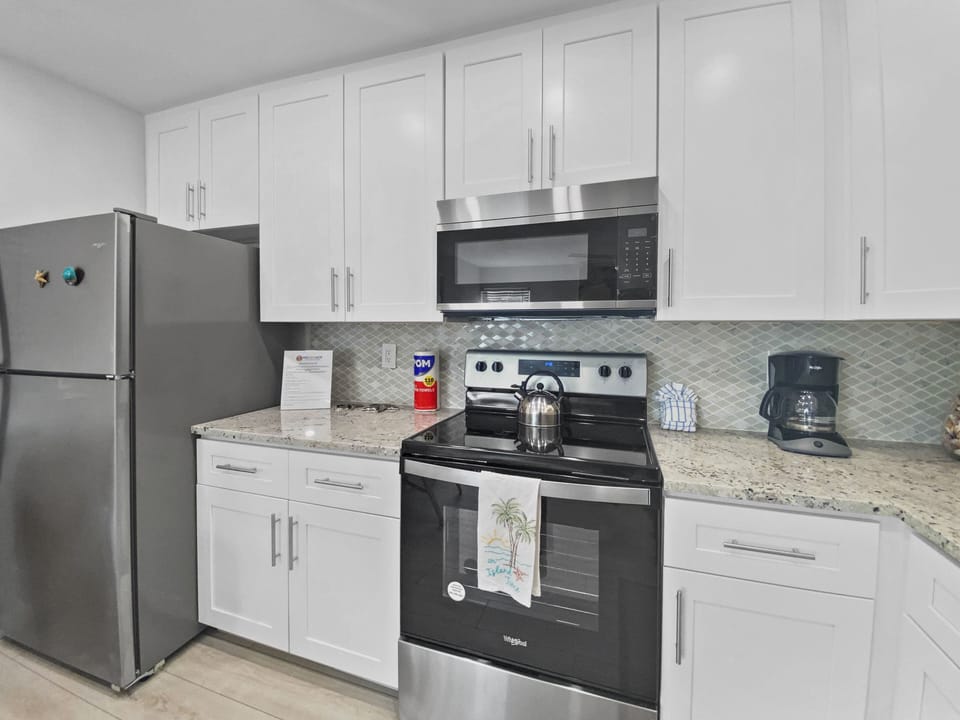 Full kitchen layout with refrigerator, stove, microwave, and granite countertops