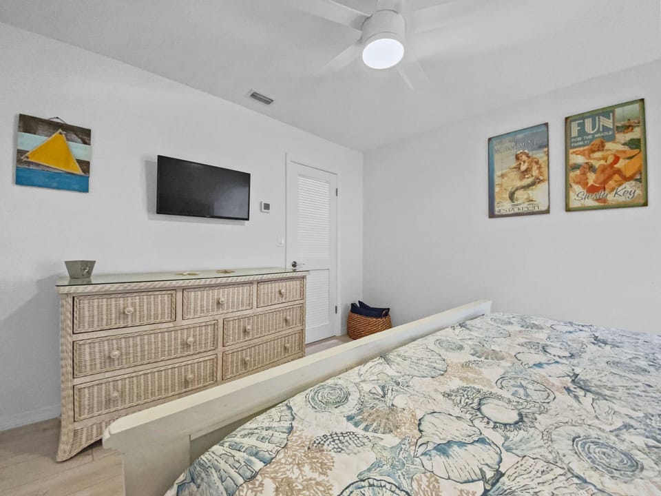 Bedroom with wall-mounted TV, dresser, and coastal décor