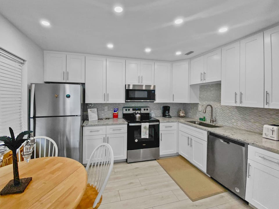 Updated kitchen with stainless steel appliances, white cabinets, and island seating