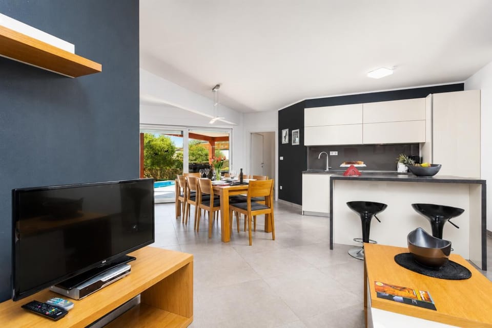 Open-plan living room with sofa, dining area, kitchen, A/C, WiFi internet, and satellite TV
