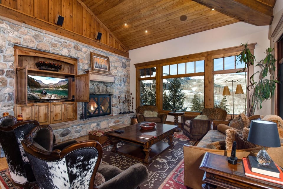     Cozy rustic living room with fireplace and stunning mountain views outside.