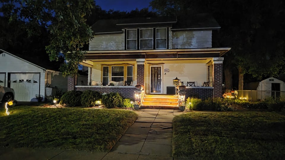 Front- Night: Warm lights transform the 1800s porch into a cozy evening retreat.