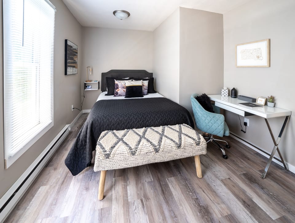 First queen bedroom, with TV, desk, charging pots, lamp, extra blanket, and fan