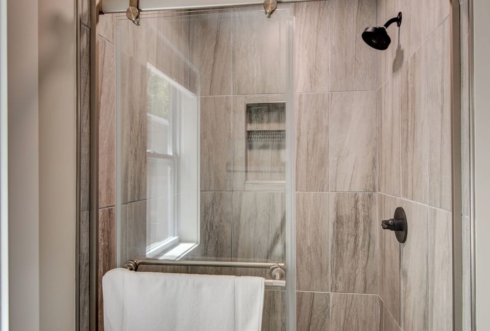 Clean, modern shower with floor-to-ceiling tile and a built-in niche. A fresh towel is always waiting for you.