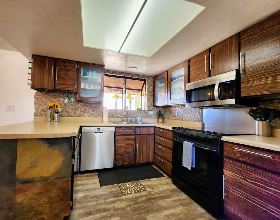 Kitchen features electric stove/oven, microwave,  pots & pans, and dishes
