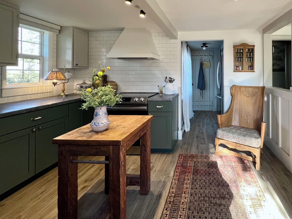 Custom zinc counters, antique rug, butcher block table and smokey green cabinets