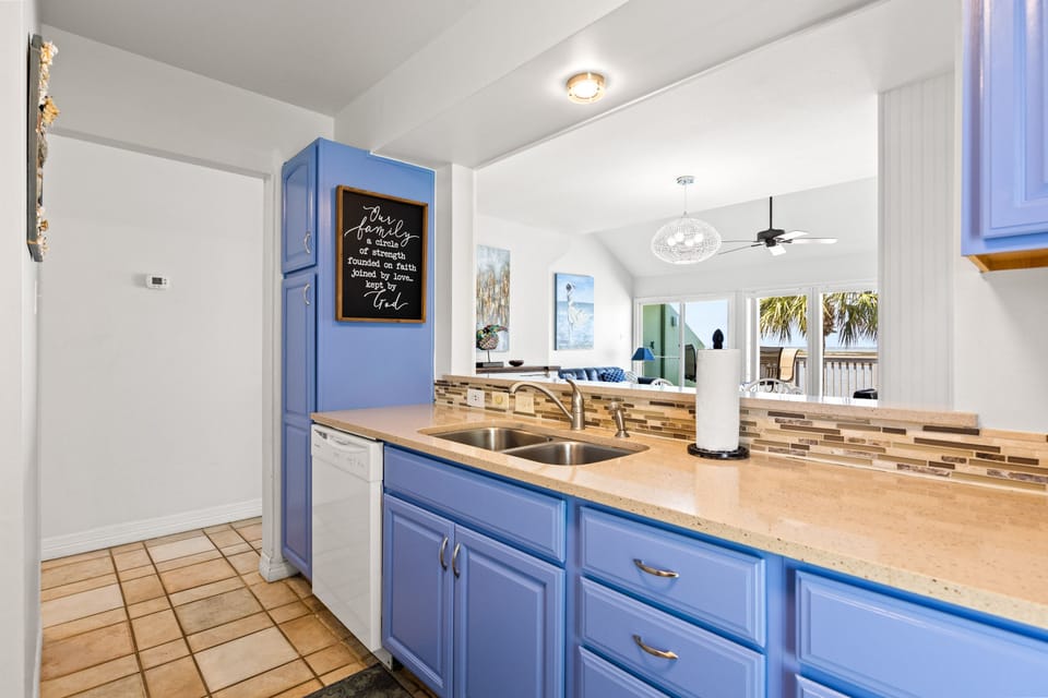 Your bright blue kitchen features warm wood countertops and opens to the living area, creating a welcoming coastal vibe.
