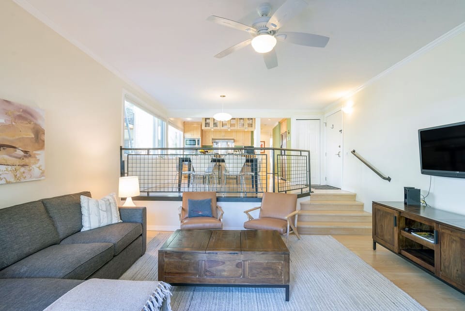 Inviting, light-filled living room with a gas fireplace and private deck, offering great entertaining space just four steps down from the kitchen.