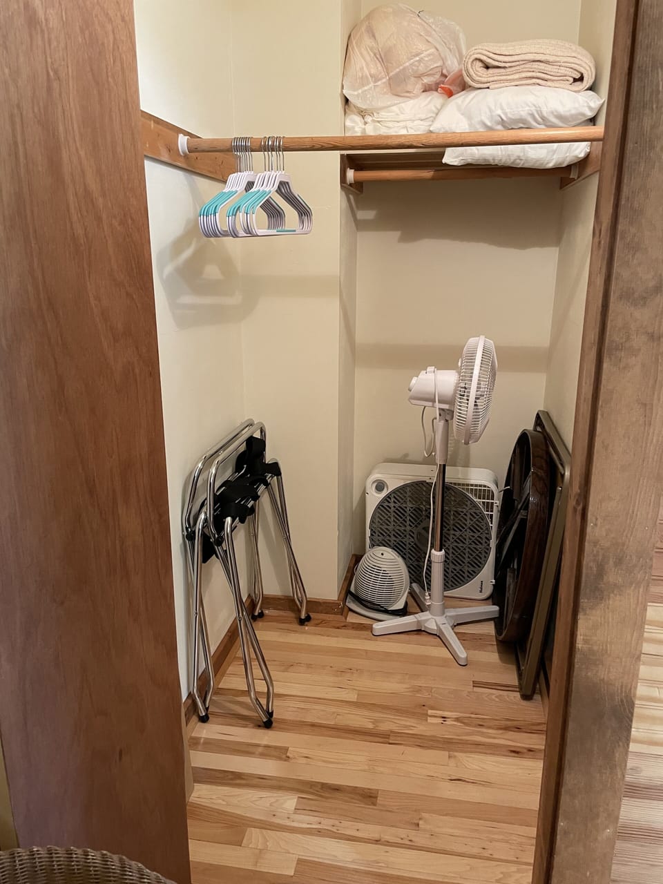 Master bedroom closet w/ extra pillows, blankets, luggage rack & fans. 