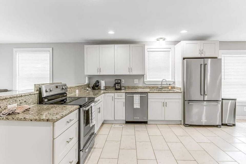 Modern kitchen with pristine white cabinetry and silver finishes.