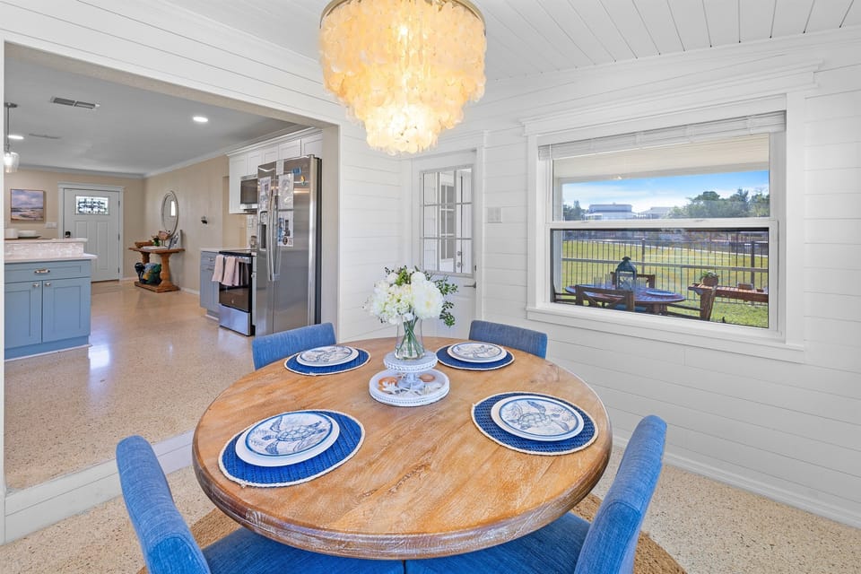 Bright coastal dining space for four with water views—perfect for slow breakfasts, family meals, or evening wine.
