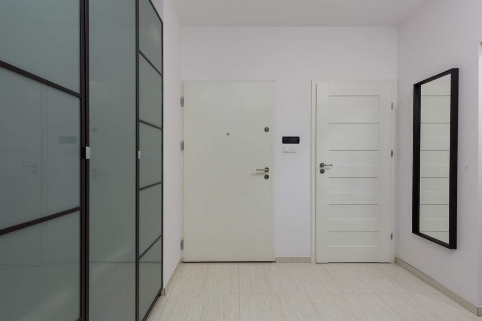 Hallway view featuring a sleek sliding wardrobe, white doors, and minimalist style.
