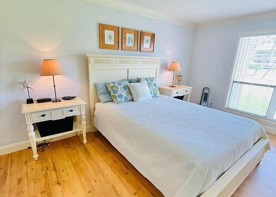 Your coastal-inspired bedroom features crisp white linens, ocean-blue accents, and warm wood floors for peaceful nights.