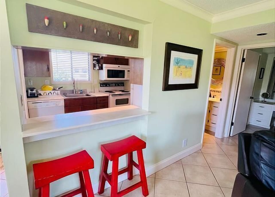 Your modern kitchen pass-through creates the perfect breakfast bar setup, complete with cheerful red stools for casual dining and coffee breaks.