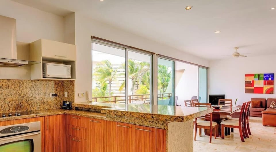 Open kitchen and dining area with granite countertops and natural light from sliding glass doors.
