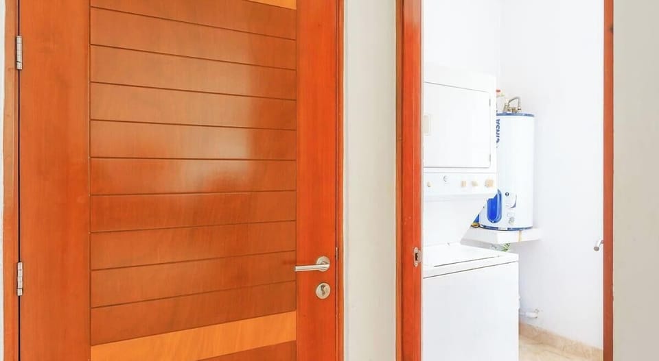 Laundry area with stacked washer and dryer behind a wooden door.