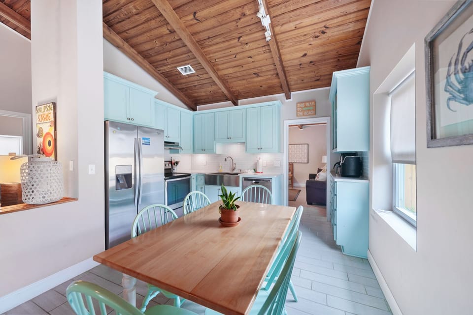Gather around this charming wooden dining table beneath exposed beam ceilings, where your turquoise kitchen awaits home-cooked meals.