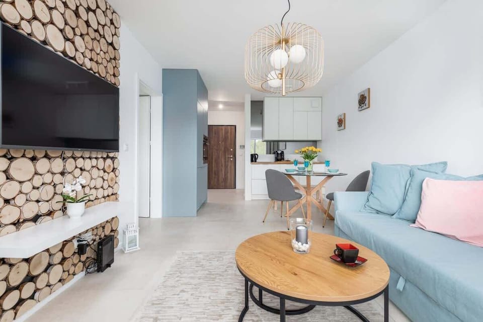 Another angle of the living room, showcasing the round coffee table, decorative logs, and cozy seating arrangement. The natural decor elements add warmth and character to the space.