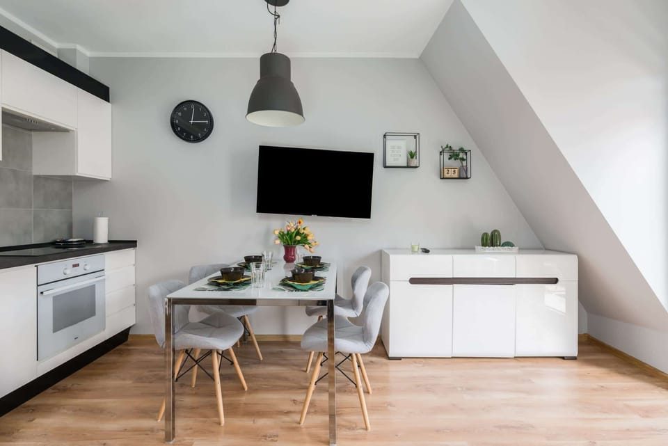 Living room corner with a dining table, TV, and bright natural lighting.
