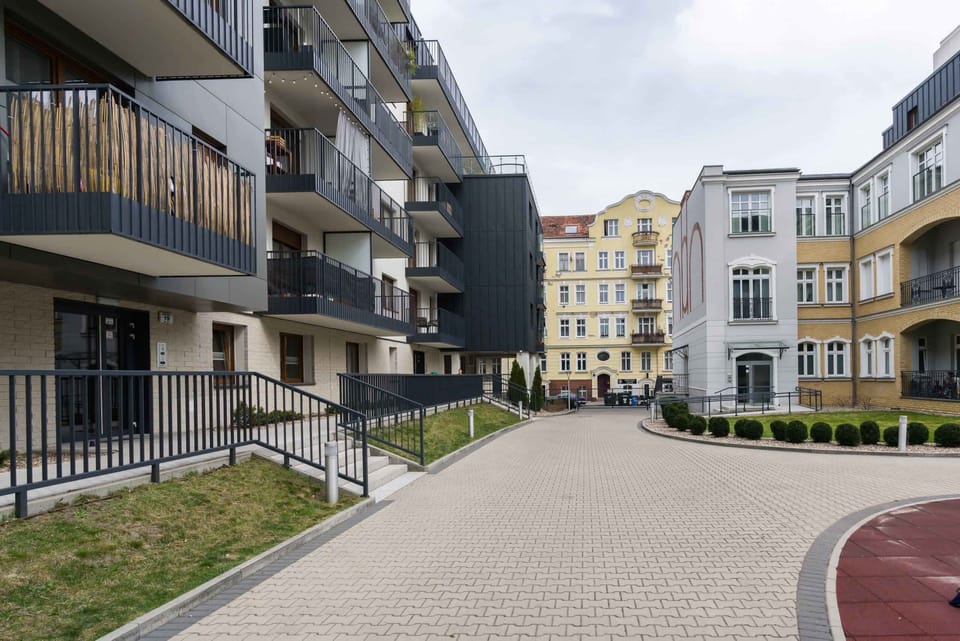 Residential courtyard with green spaces and pathways surrounded by modern buildings.
